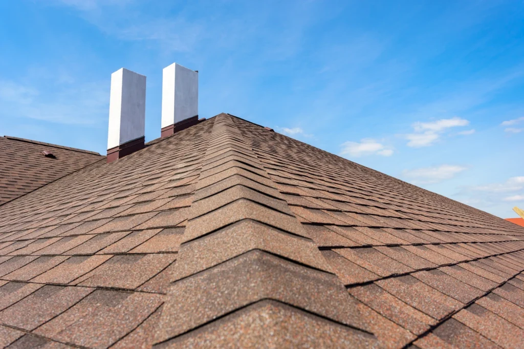 close up of sloped asphalt roofing system with brown shingle colors
