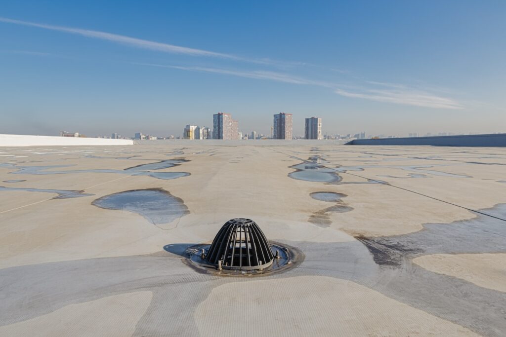 flat roof drain with cityscape in the background