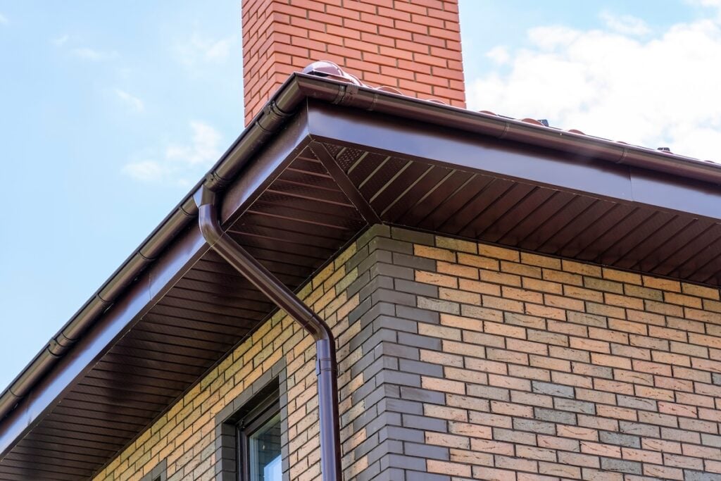 close-up view of house with brown roof and filing of roof overhangs with metal soffits with vents