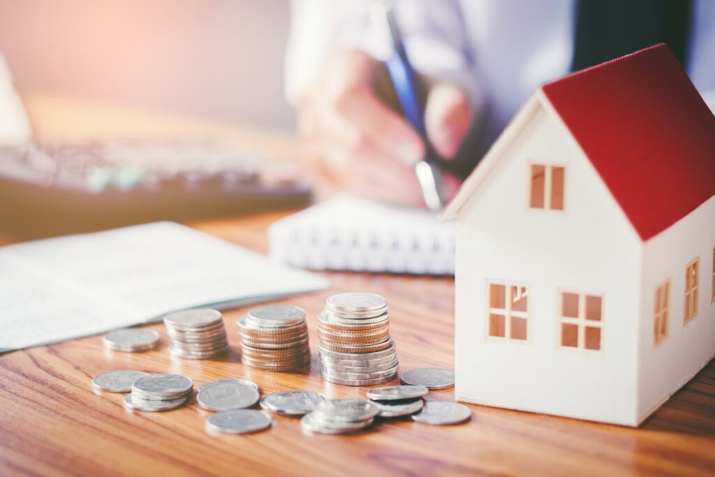 Stacks of coin next to a small home figurine