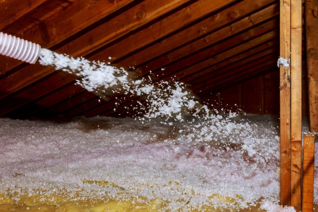 Worker Spraying thermal insulation layer under the roof house attic insulation
