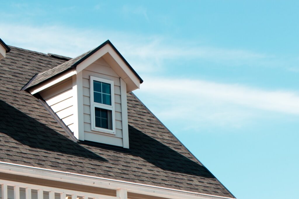 Close-up image of an apartment building window and new asphalt roof shingles