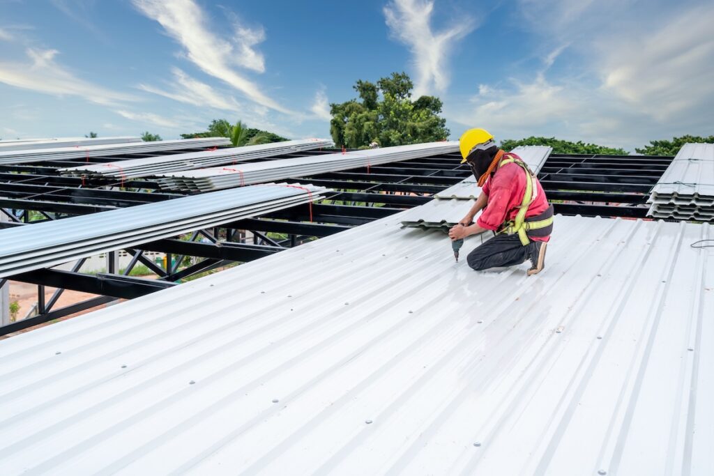 A roofer installed metal sheet as a roof for a large structure