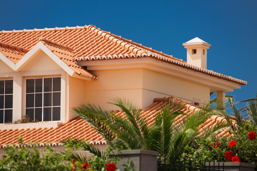 Orange tiled roof of a large house with pretty landscaping