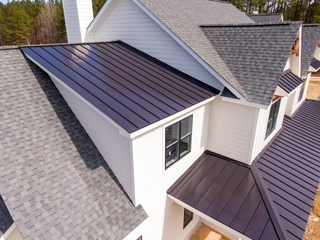 Sunny Daytime Drone Images of a Custom Home in the Final Stages of Construction. It Features a Roof With Architectural Asphalt Shingles and Standing Seam Accents.