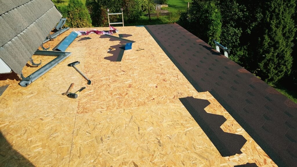 Installing asphalt roofing shingles, work in progress. Roof repair and installation, panoramic view. House repair and building concept.