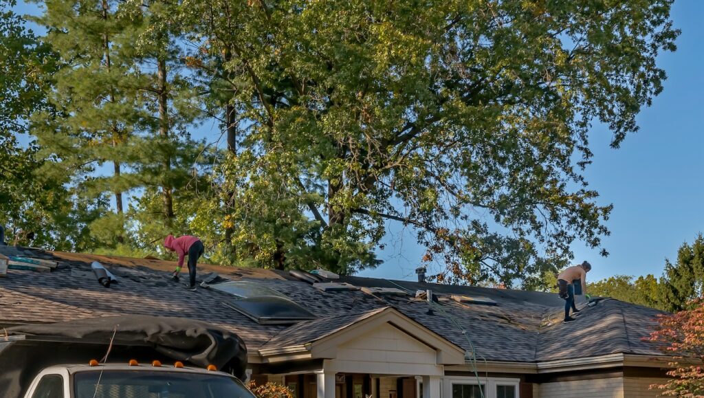 Roofers removing old material from a house in preparation for storm damage repair